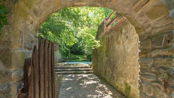 Un arco in pietra che dà accesso a un sentiero immerso nel verde.