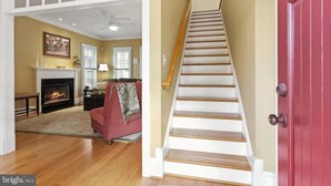 A staircase leading to a second floor, a fireplace in the living room, and a red door. - The Houstonia, 3 bedroom single family home near DC (Arlington)