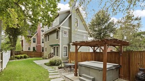 A two-story house with a covered patio area, a hot tub, and a wooden fence. - The Houstonia, 3 bedroom single family home near DC (Arlington)