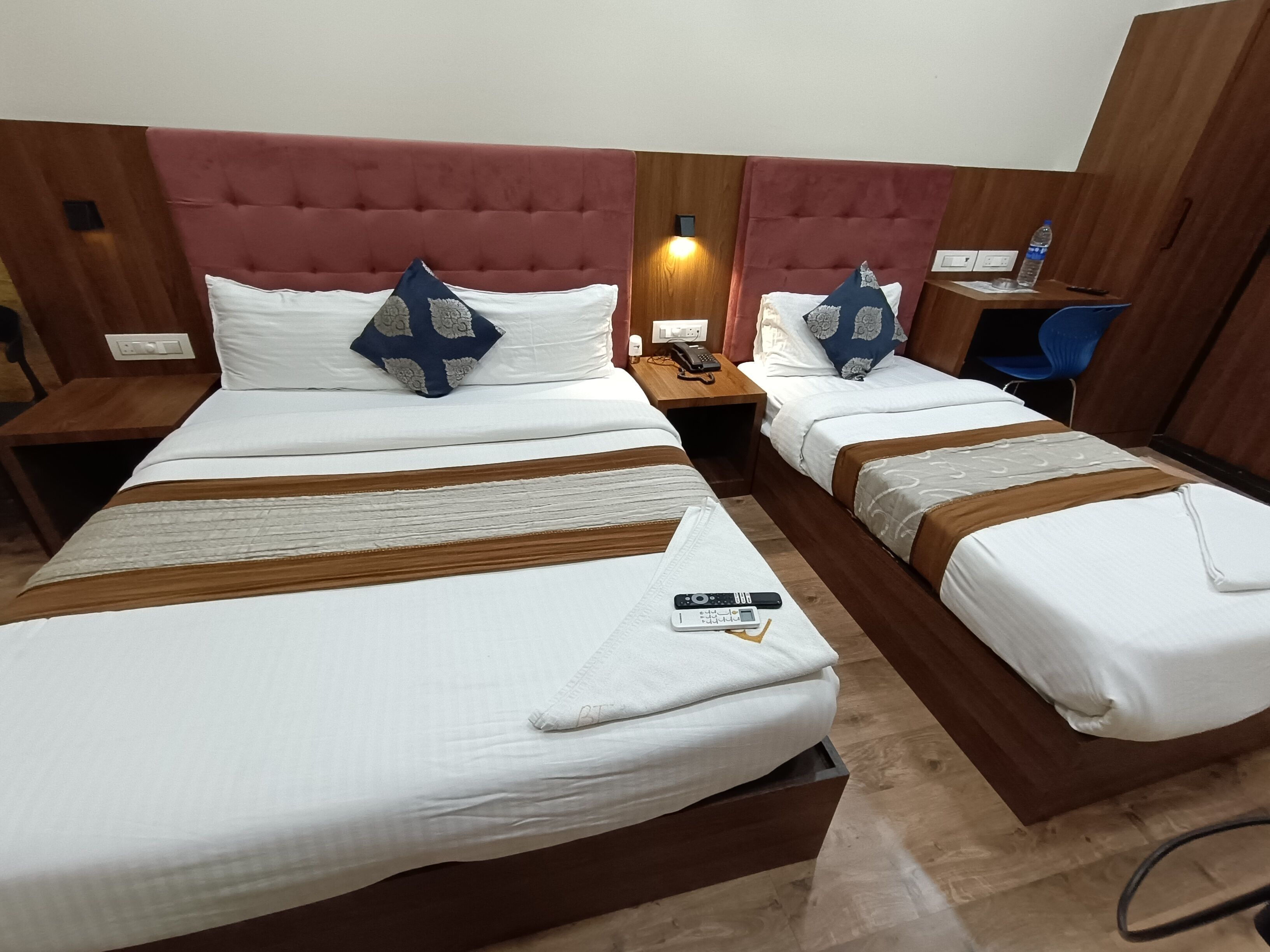 A hotel room with two beds, each with a headboard, bedside tables, and a lamp.