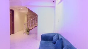 A modern interior with a blue sofa, a staircase, and a ceiling with LED lighting. - Hotel Best (Mumbai)