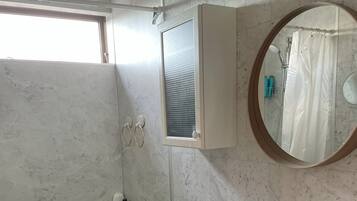 Een badkamer met een groen bad, een witte wastafel, een toilet, een spiegel en een raam met een handdoekhouder.