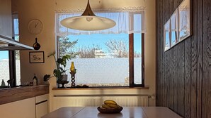 Una cucina moderna con mobili in legno, un tavolo da pranzo con una panca, una lampada a sospensione, una finestra con vista e un termosifone.