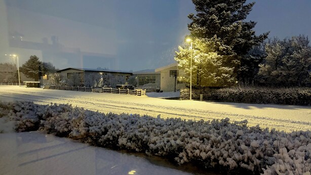 Paesaggio innevato con un edificio, una recinzione e un lampione.
