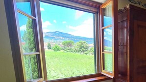 Een kamer met een groot raam dat uitzicht biedt op een groen landschap en heuvels in de verte.