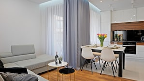 Un salon moderne comprenant un canapé, une table à manger avec des chaises et un coin cuisine avec des placards et des appareils électroménagers.