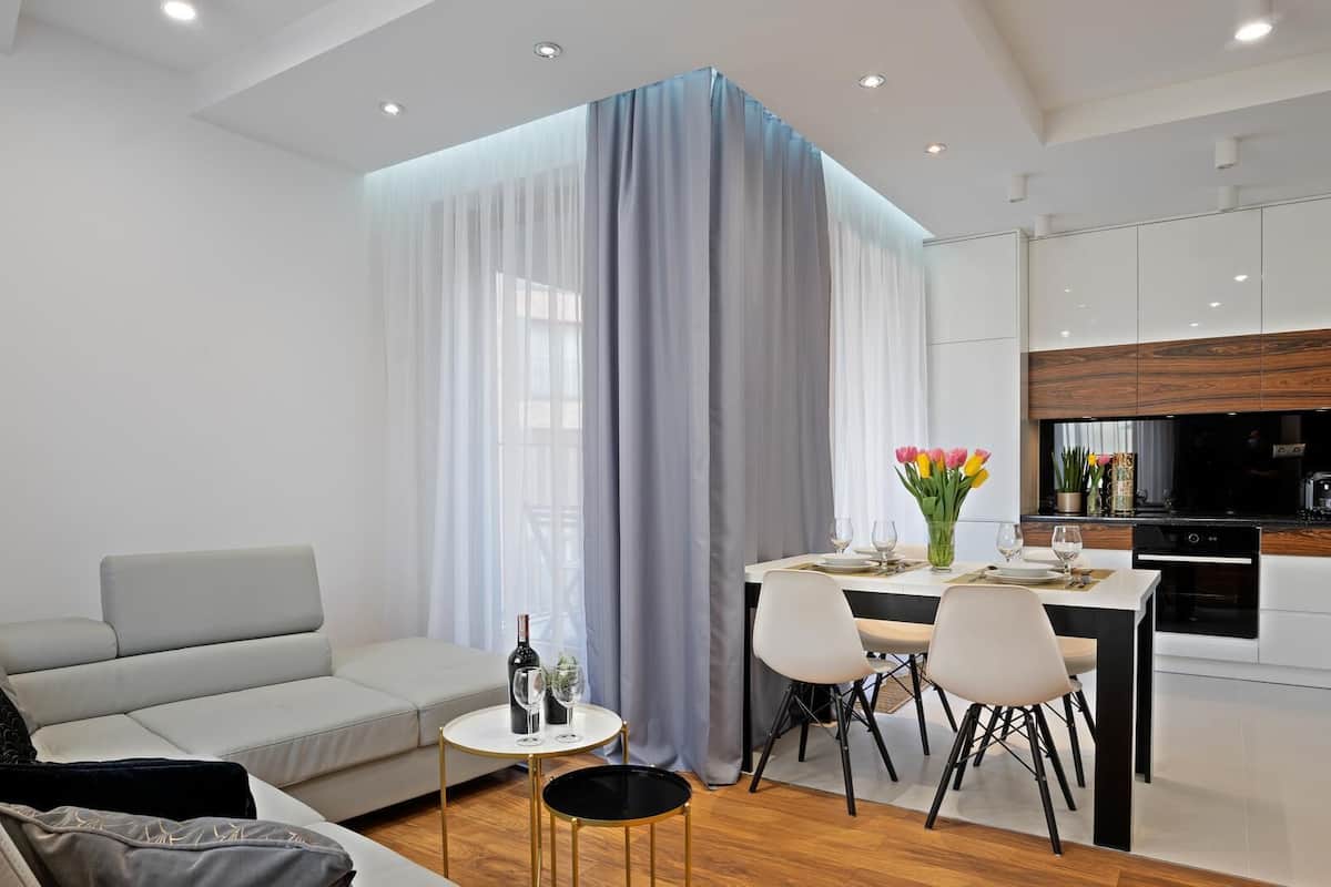 Un salon moderne comprenant un canapé, une table à manger avec des chaises et un coin cuisine avec des placards et des appareils électroménagers.