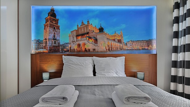 Une chambre d’hôtel avec un grand lit, deux oreillers et deux serviettes pliées.