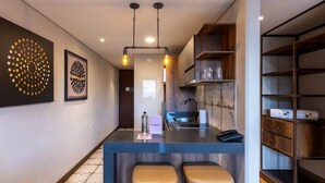 A modern kitchen with a bar area, two stools, and a built-in shelf unit.