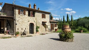 A stone house with a gravel driveway, a staircase, and potted plants. - Holiday home in Cortona (Cortona)