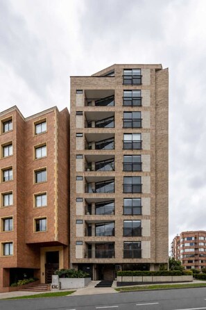 A multi-story residential building with a brick facade, large windows, and a flat roof.