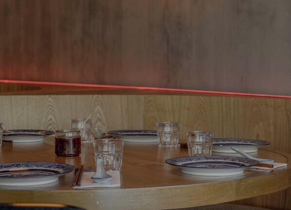 A round dining table with plates, glasses, and a jar of jam.