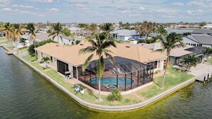 A waterfront property with a pool, a covered patio, and a view of the surrounding neighborhood. - CasaSuLago Sunset Lakefront, Saltwater Pool & Spa, Fishing, Kayaks & Game Room! (Cape Coral)