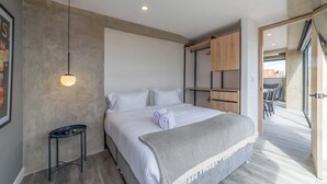 A modern bedroom with a bed, bedside table, and a wardrobe.