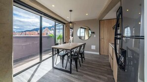A modern kitchen with a dining area, large windows, and a view of the city.