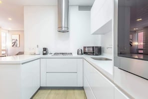 Una cocina moderna con armarios blancos, una campana extractora de acero inoxidable, un microondas y un horno empotrado.