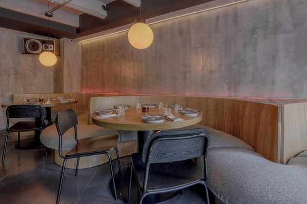 Ein Restaurantinneres mit einem runden Tisch, gedeckt für vier Personen, umgeben von gepolsterten Sitzgelegenheiten.