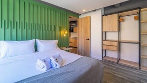 A modern hotel room with a green accent wall, a large bed with white linens, a wooden wardrobe, and a small kitchen area. - NOK Stunning 1 Br in Chapinero (Bogotá)