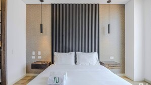 A modern hotel room with a large bed, two bedside tables, and a textured wall.