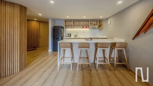 A modern kitchen with a central island, bar stools, wooden paneling, and built-in shelves. - NOK Stylish 3BR Apt & Fast Wi-Fi Bogotá (Bogotá)
