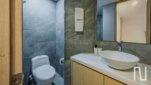 A modern bathroom with a toilet, a sink, and a mirror. - NOK Stylish 3BR Apt & Fast Wi-Fi Bogotá (Bogotá)