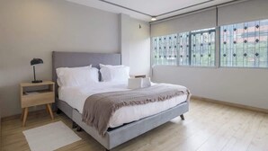 Camera da letto moderna con un letto, comodini, un tavolino da notte e un'ampia finestra con vista.