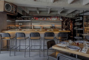 Un espace bar avec des tabourets, un comptoir et une étagère remplie de bouteilles.