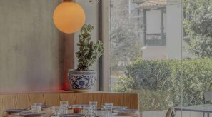 A dining table set with plates, glasses, and a decorative vase with a plant.