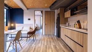 Una cucina moderna con pensili in legno, un'area pranzo con tavolo e sedie bianche e un soffitto con travi a vista.