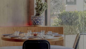 Un'area pranzo con un tavolo apparecchiato per quattro persone, una pianta in vaso e un lampadario.