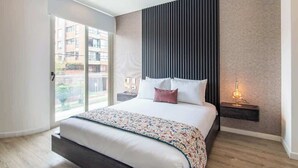 A modern bedroom with a large bed, a sliding glass door to the outside, a wall-mounted nightstand, and a bedside lamp. - NOK Modern  3BR in Usaquén (Bogotá)