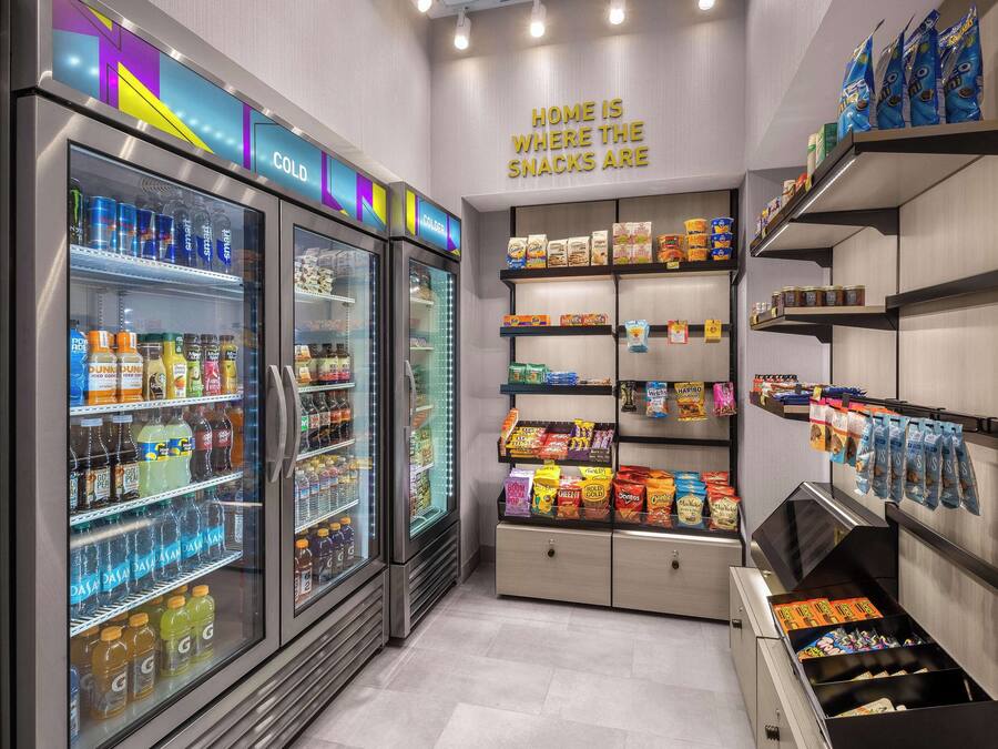 Una sección de aperitivos y bebidas con vitrinas refrigeradas y estantes llenos de productos.