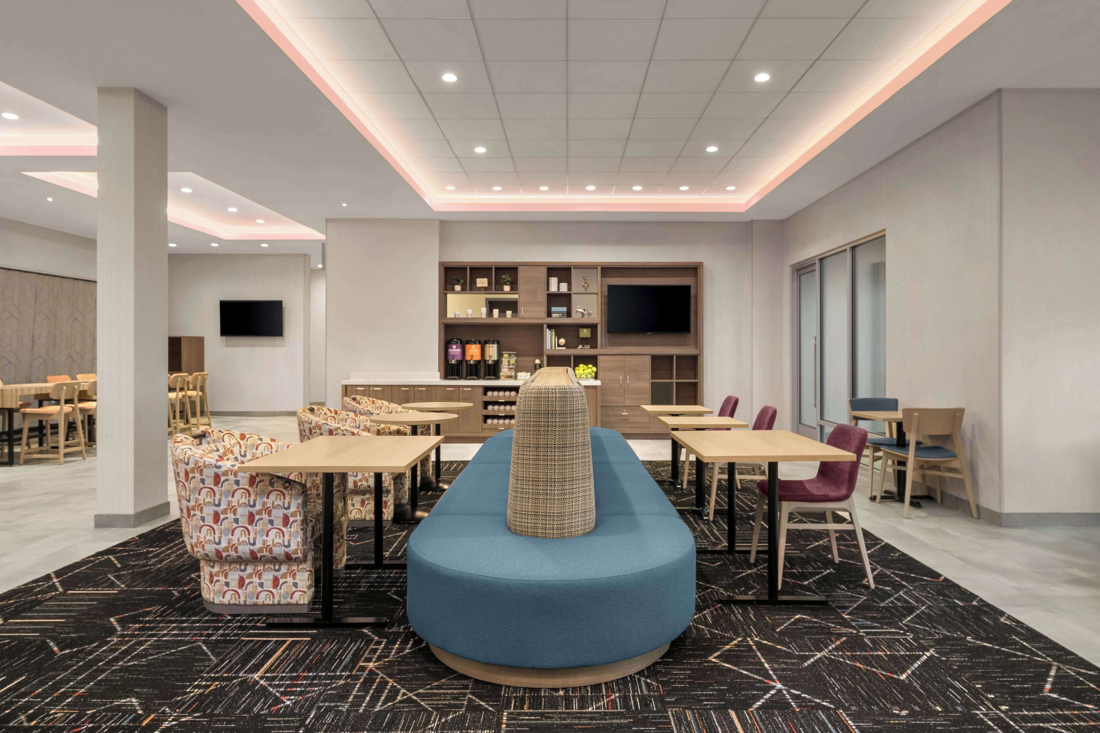 Un comedor moderno con una zona de estar central azul, varias mesas y sillas.