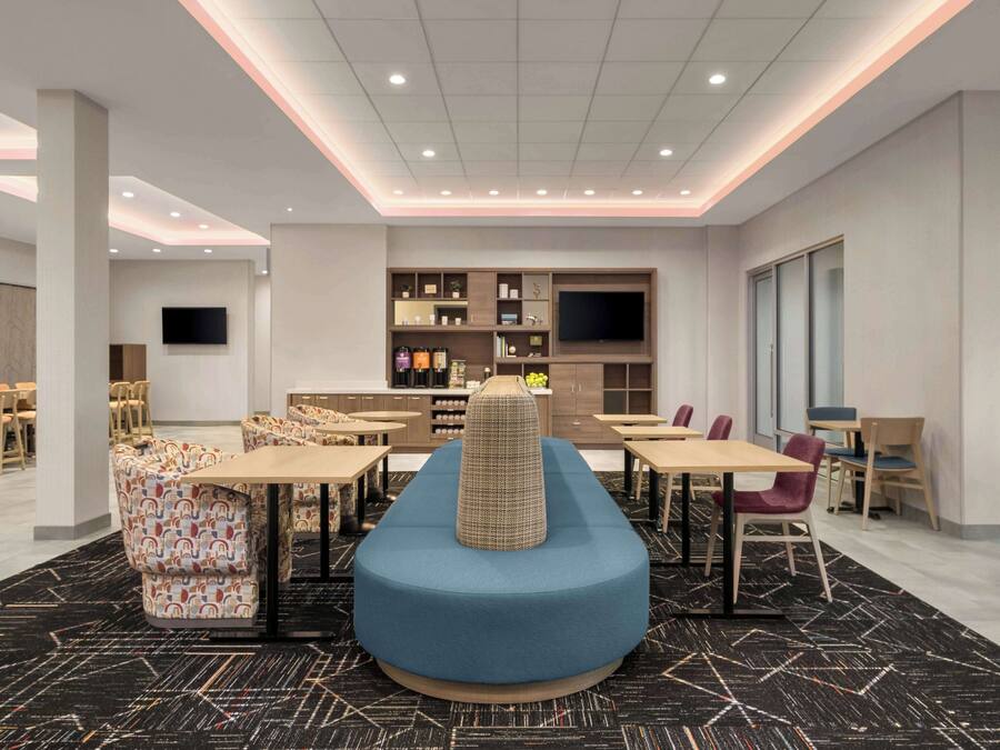 Un comedor moderno con una zona de estar central azul, varias mesas y sillas.