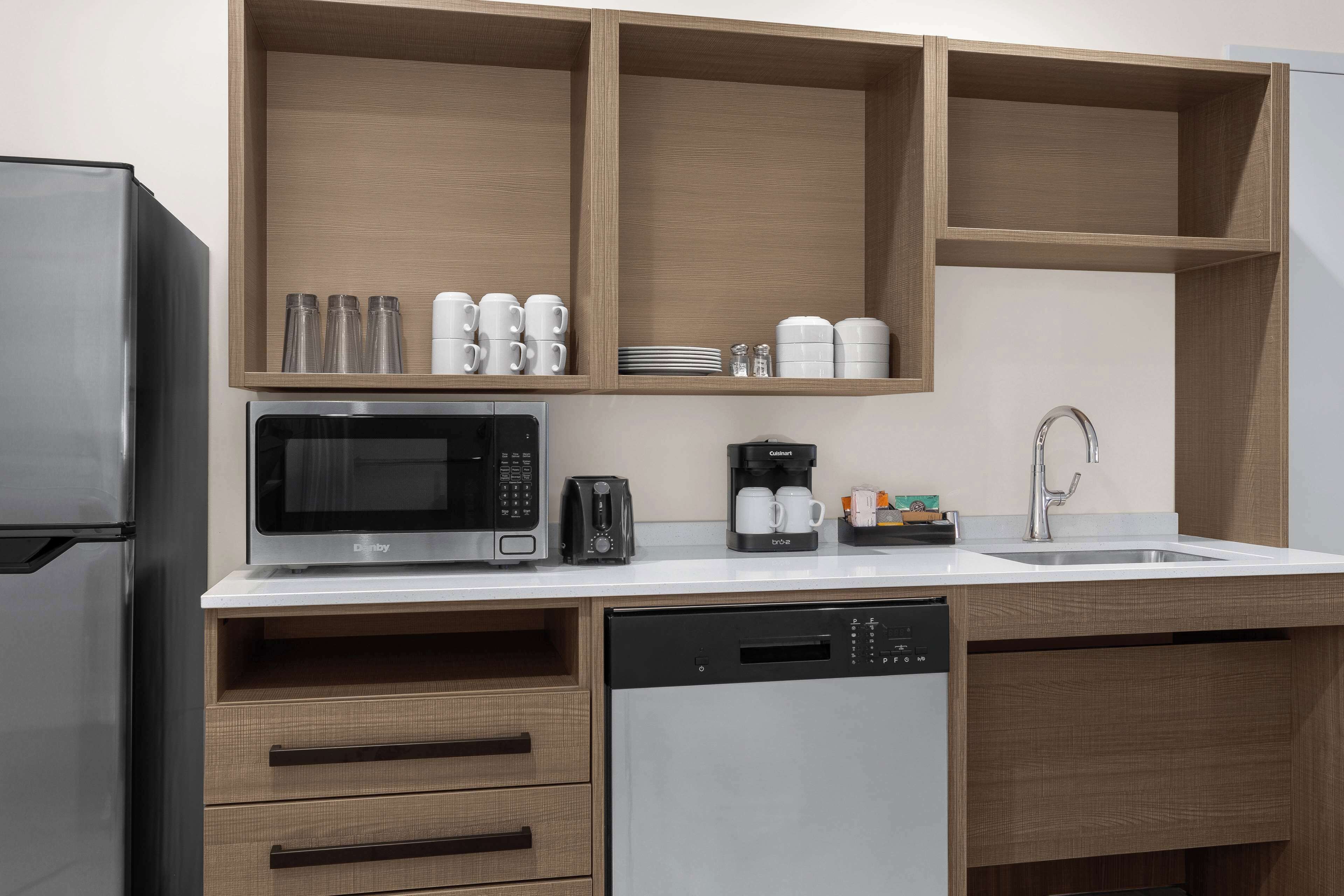 A modern kitchen with a built-in microwave, coffee maker, and dishwasher.
