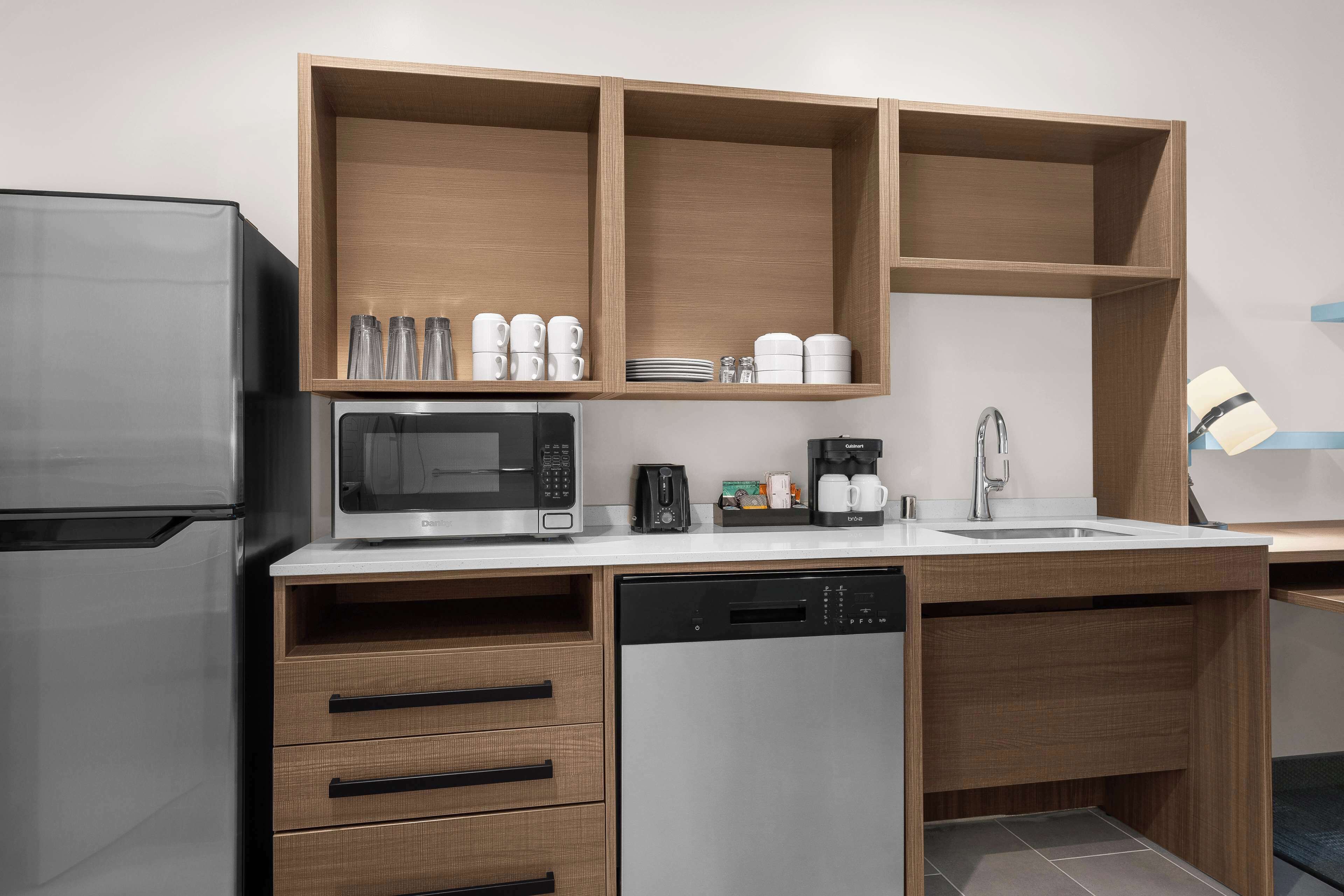 A compact kitchen with a built-in microwave, coffee maker, and dishwasher.