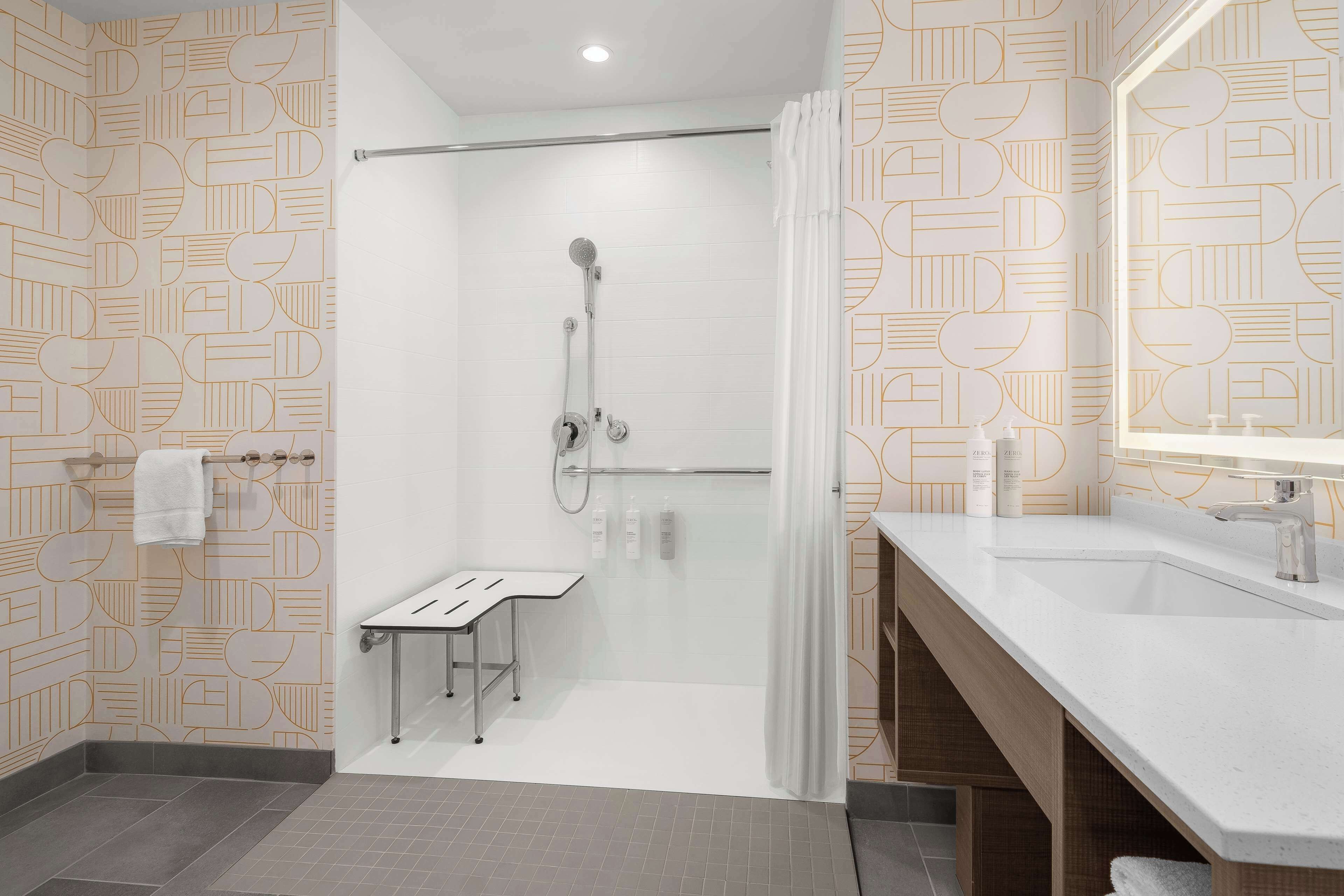 A modern bathroom with a shower, a sink, and a mirror.