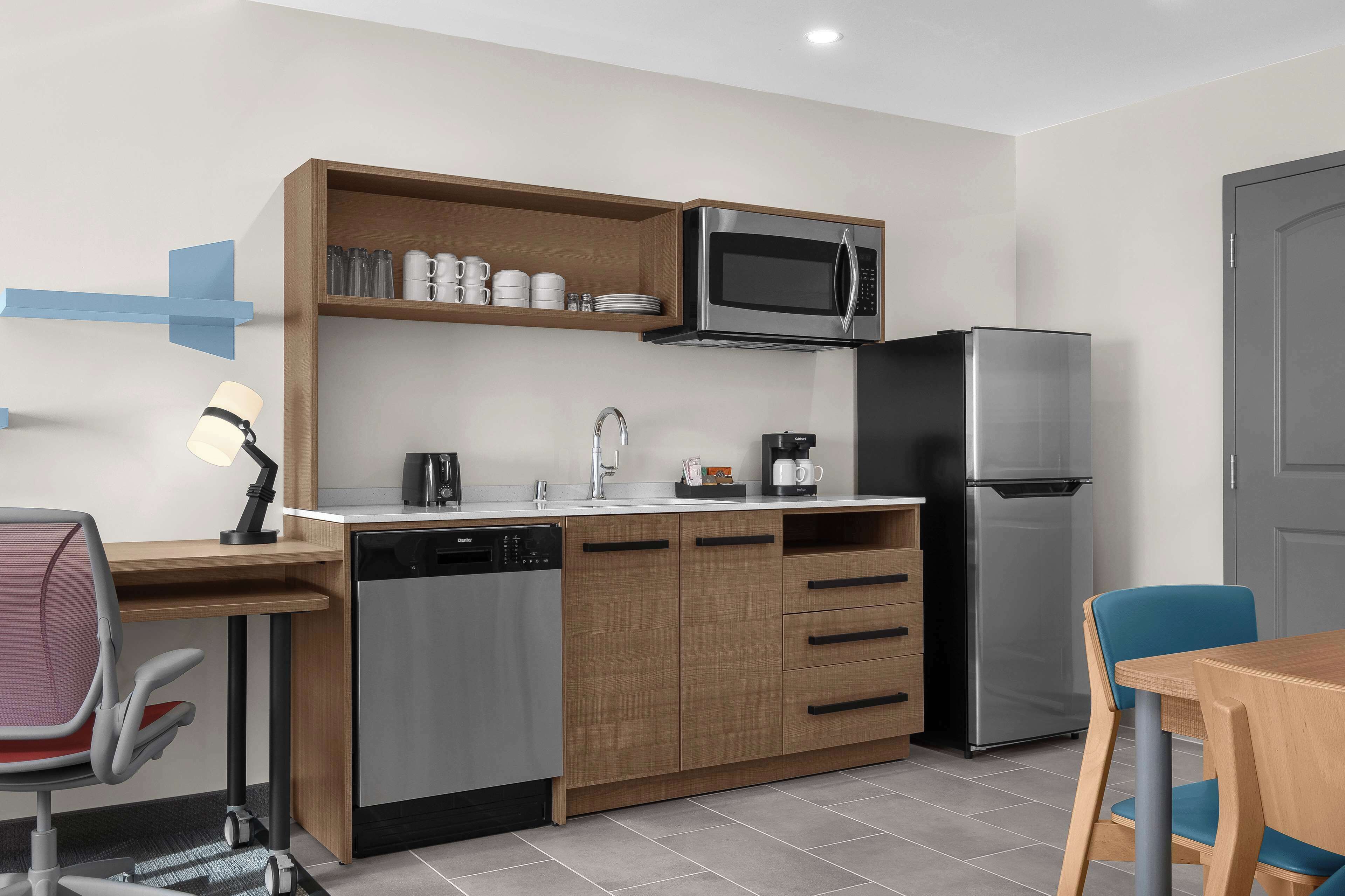 A compact kitchen with a microwave, refrigerator, dishwasher, and a small coffee maker.