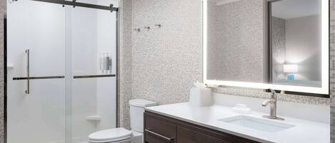 Een moderne badkamer met een glazen douchecabine, toilet, een wastafel met spiegel en een wasbak.