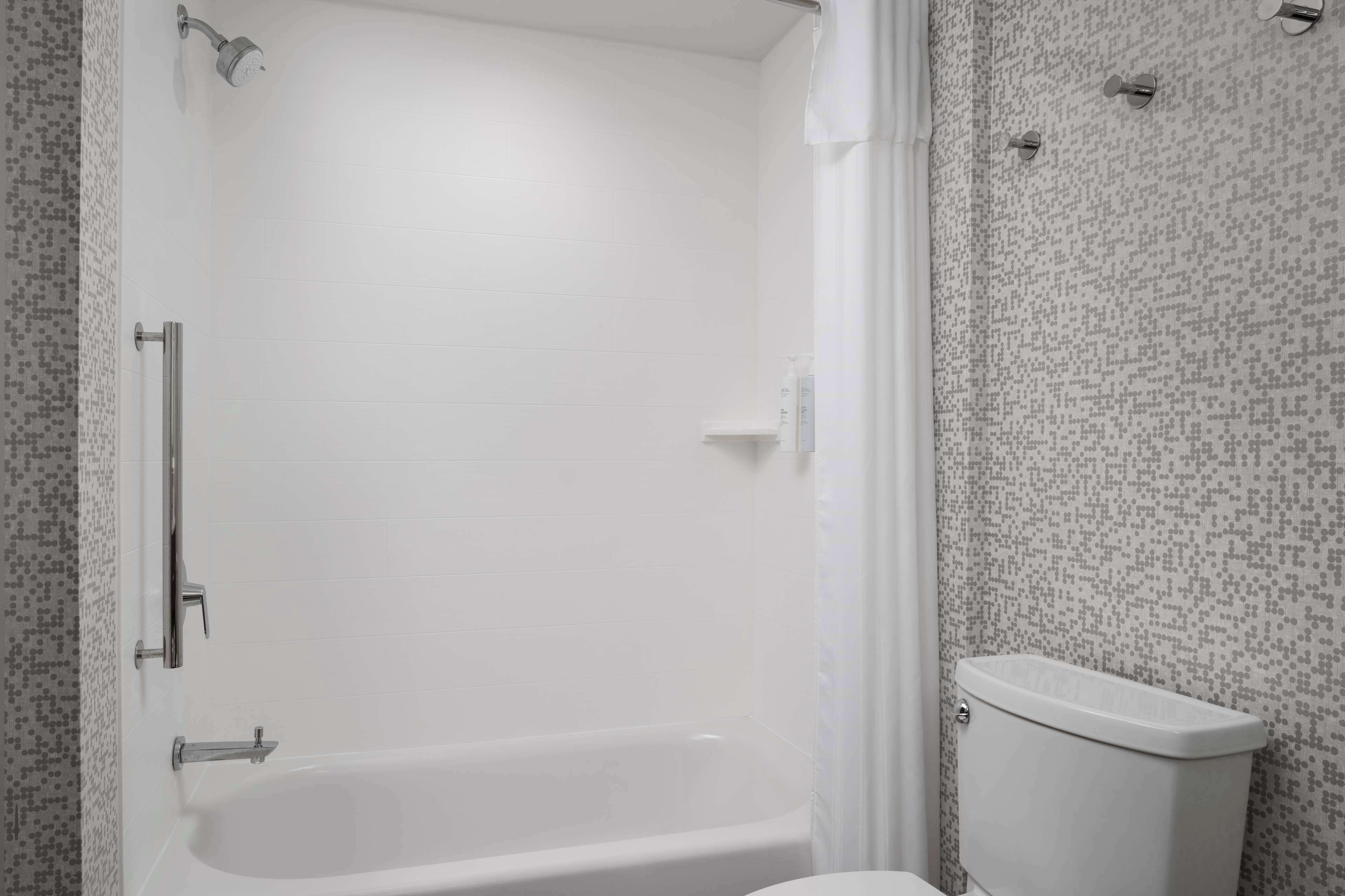 A bathroom with a white bathtub, a toilet, and a shower area.