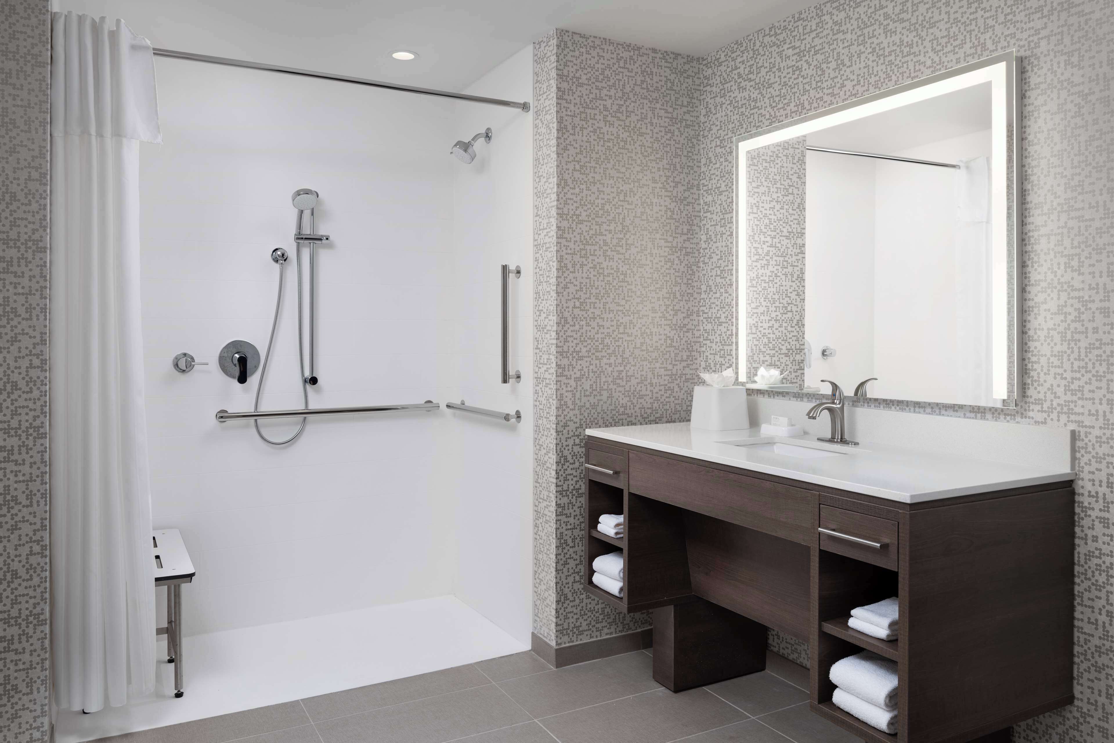 A modern bathroom with a shower, vanity, and a large mirror.