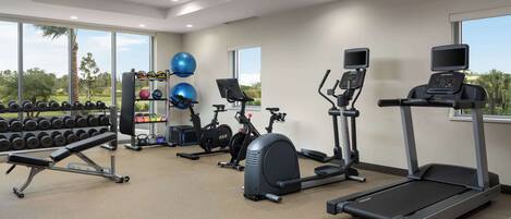 A gym with treadmills, elliptical machines, and free weights.