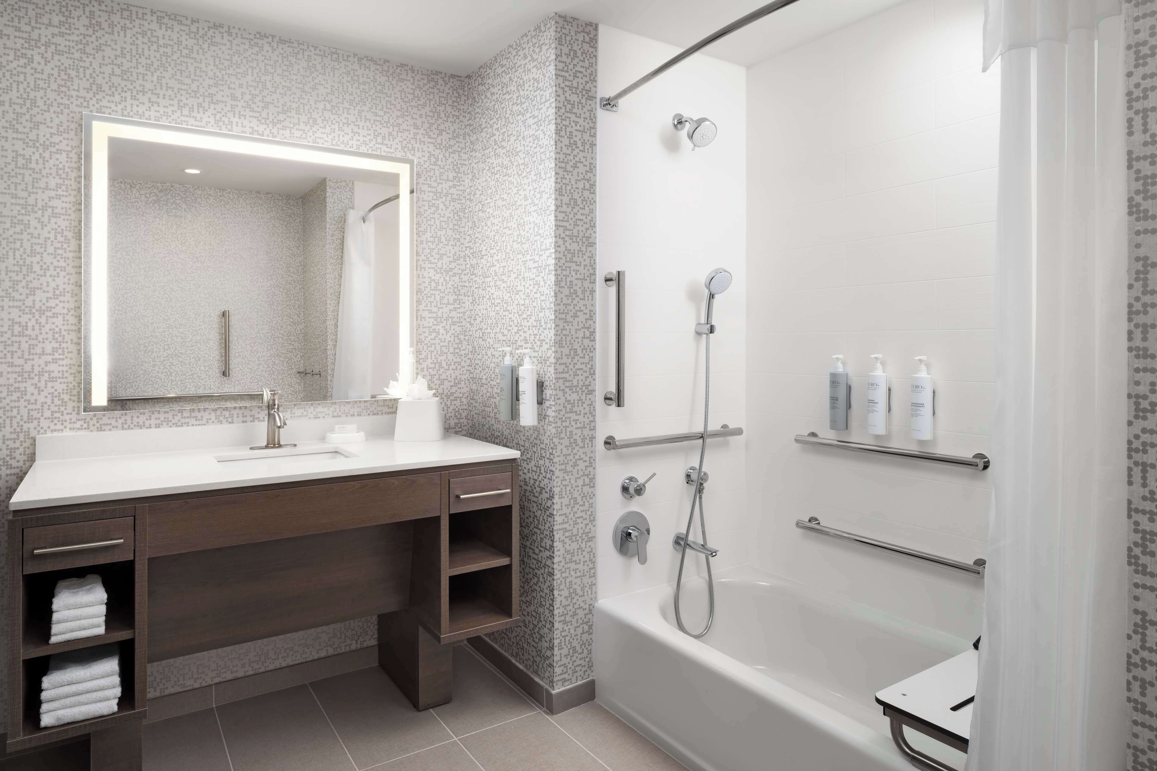 A modern bathroom with a large mirror, a bathtub, and a shower area.