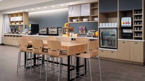 A modern kitchen with a central island, bar stools, and a refrigerator. - Home2 Suites By Hilton Winter Haven (Winter Haven)
