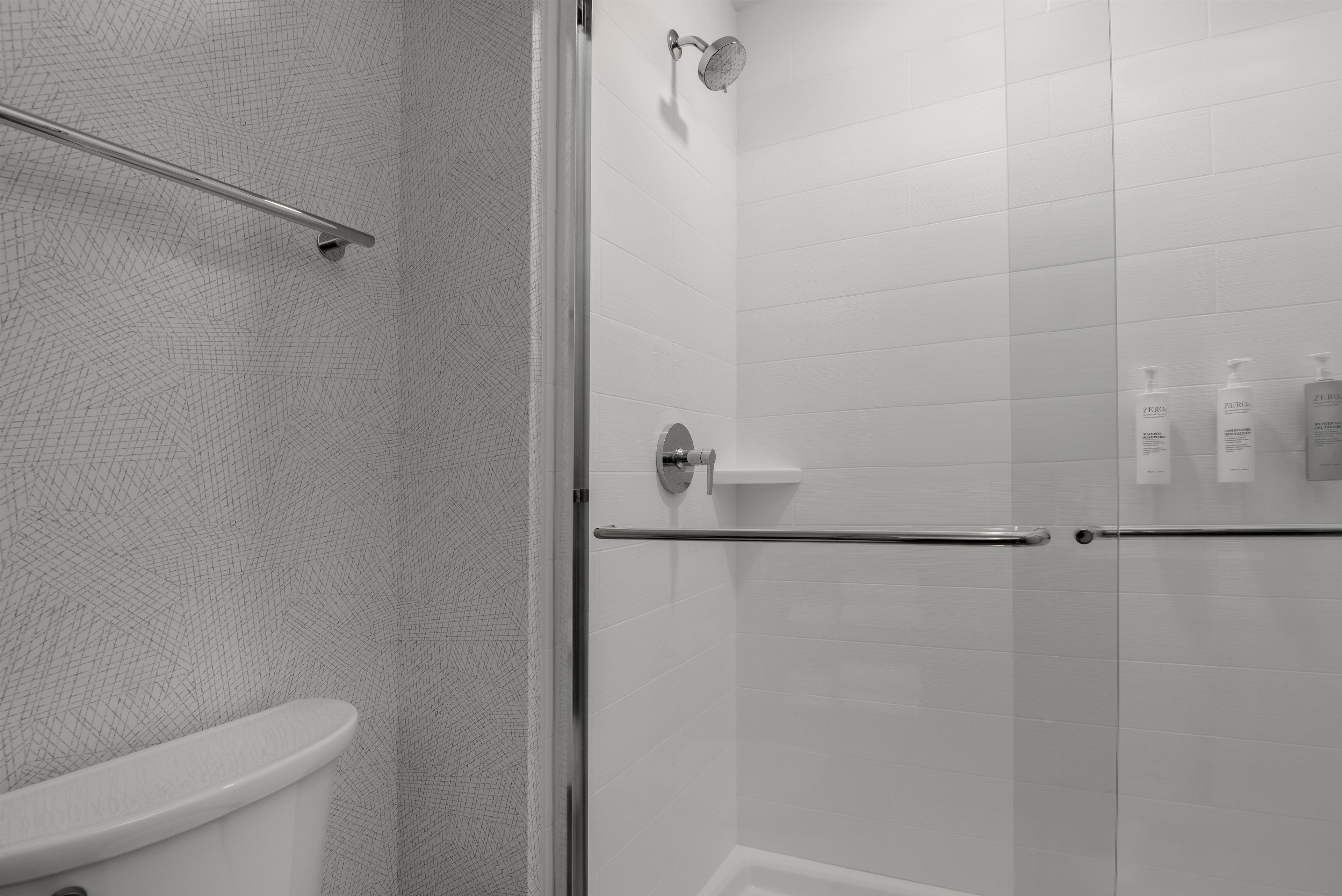 Une salle de bain moderne équipée d’une douche, de toilettes et d’une paroi de séparation en verre.