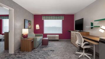 A hotel room with a bed, a desk, a chair, a TV, a lamp, and a window with a view.