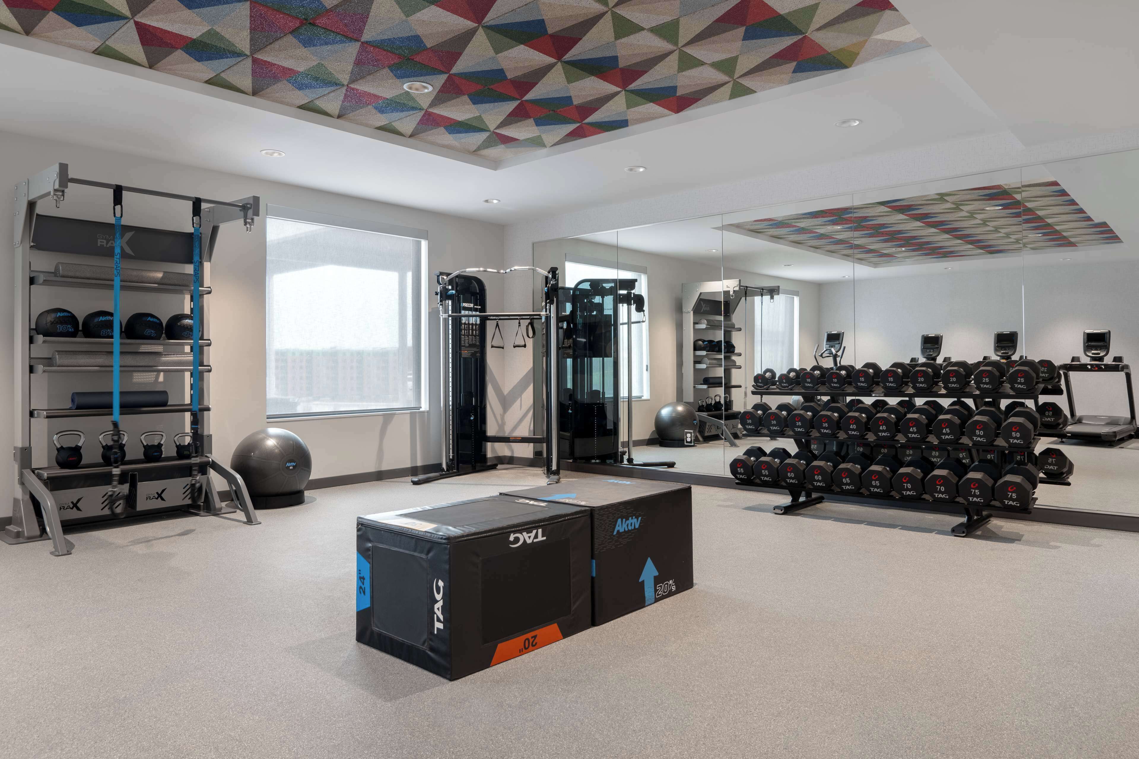 Un gimnasio moderno con equipamiento de levantamiento de pesas, pelotas de ejercicio y mancuernas.