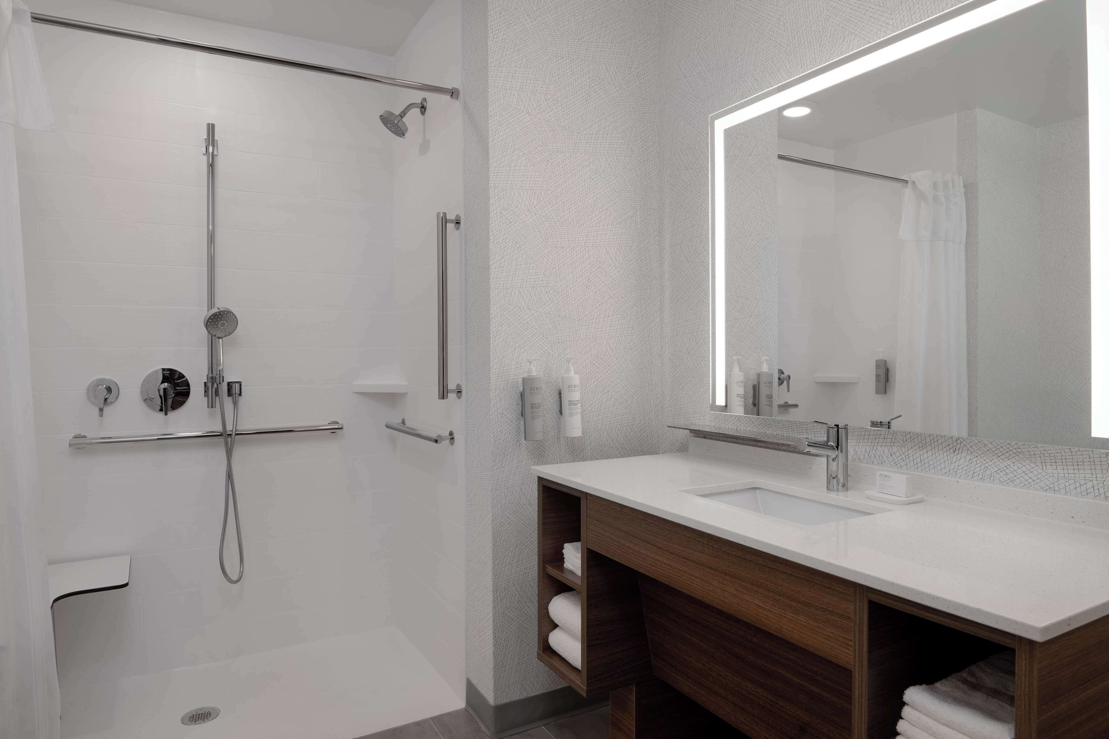 Une salle de bain moderne avec une douche à l’italienne, un grand miroir et un meuble-lavabo en bois.