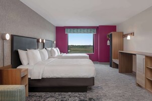 Una habitación de hotel moderna con dos camas, un escritorio y vistas al exterior.