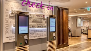 Un kiosque d’enregistrement d’hôtel doté d’un écran numérique, d’un panneau en bois et de citations inspirantes affichées sur le mur.